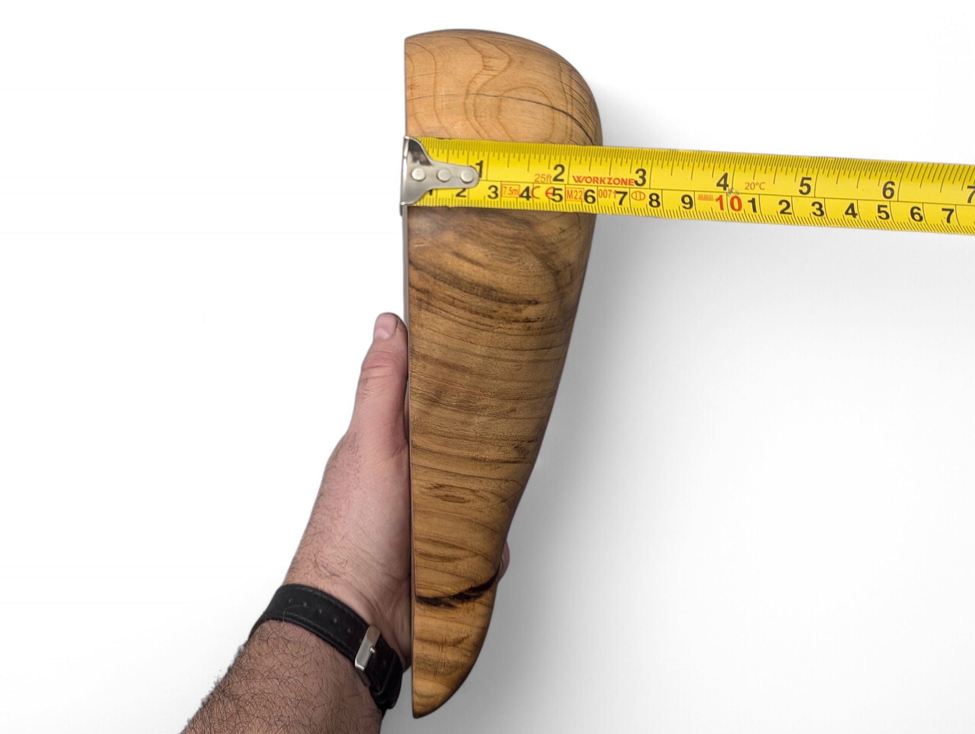 Hand holding light brown hardwood sculpture with natural grain, measured at 9 inches by yellow tape.