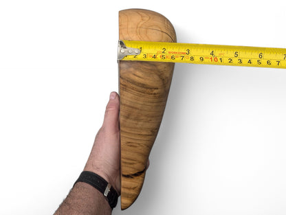 Hand holding light brown hardwood sculpture with natural grain, measured at 9 inches by yellow tape.