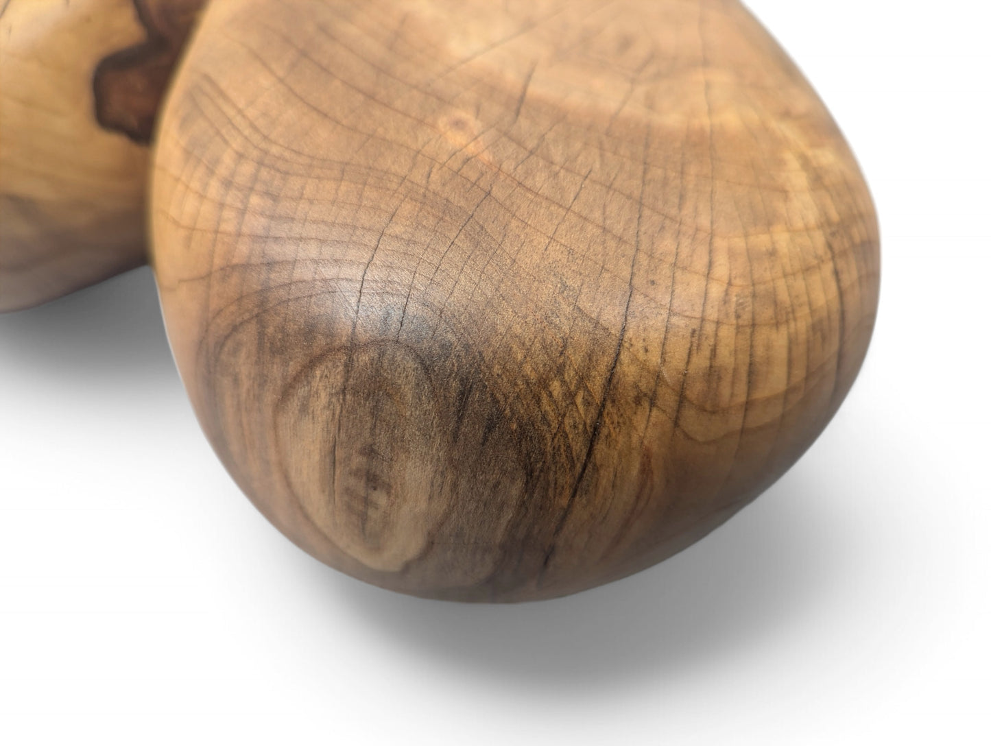 Close-up of a rounded solid wood sculpture showing rich brown natural grain, fine cracks, and an oiled finish.