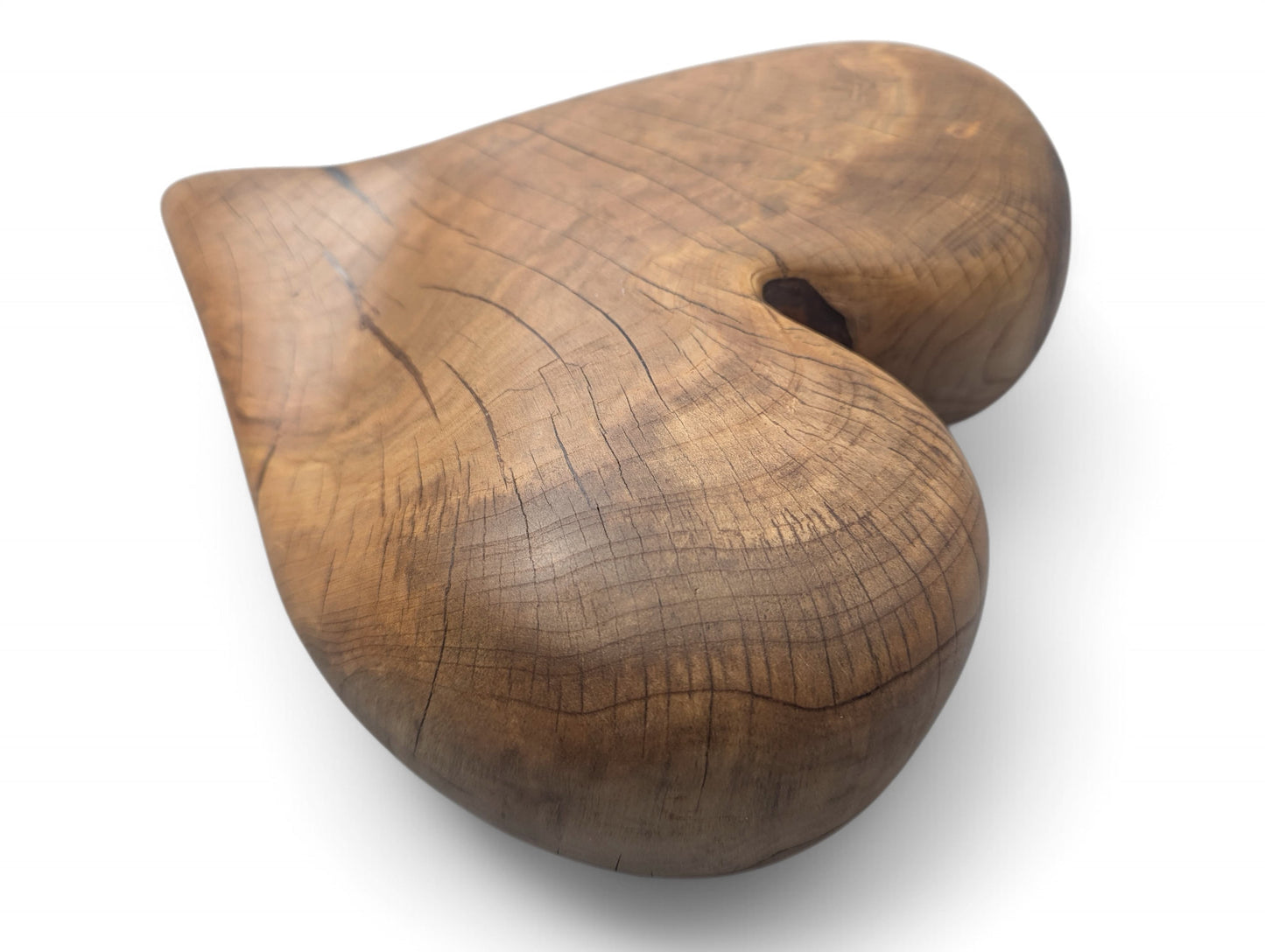 A rounded, brown, heart-shaped wood sculpture, displaying natural grain, visible cracks, and an oiled finish.
