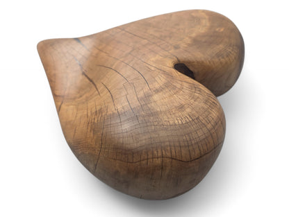 A rounded, brown, heart-shaped wood sculpture, displaying natural grain, visible cracks, and an oiled finish.