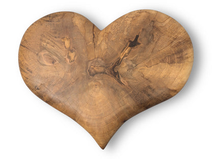 Heart-shaped hand-carved solid wood piece showing rich grain, prominent knots, and dark brown natural oil finish.