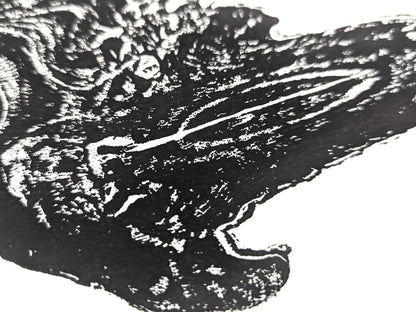 Close-up of a black and white monoprint showing an irregular, textured tree root impression on white paper.