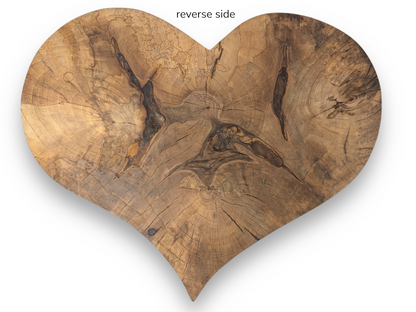 Reverse side of a heart-shaped wood slab, displaying natural grain, prominent knots, and cracks.