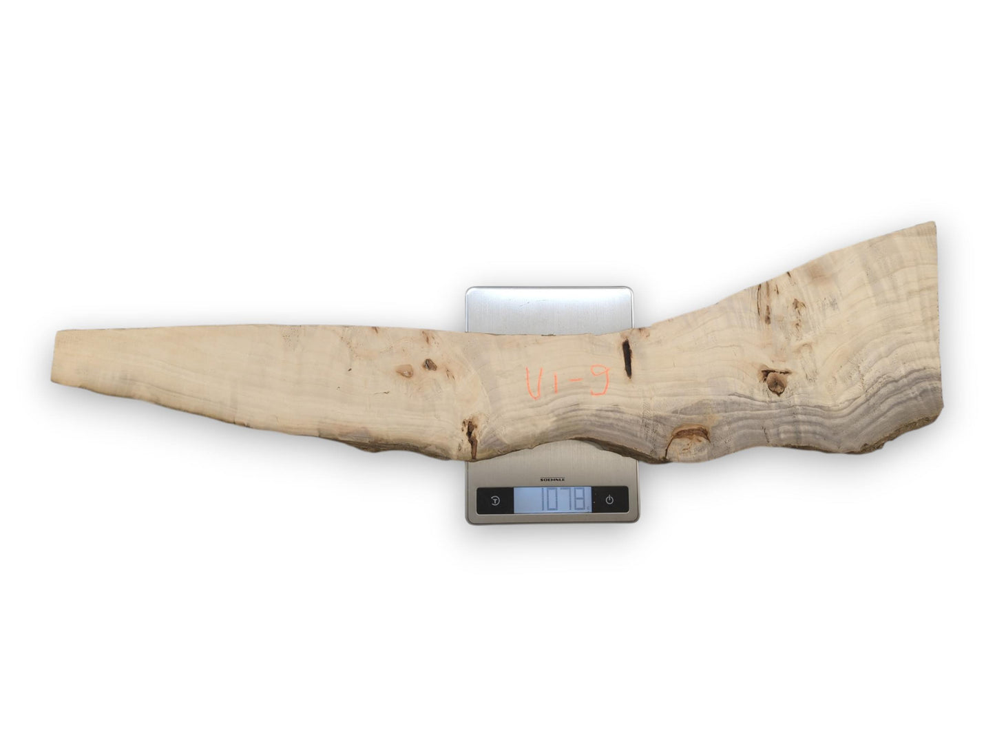 An overhead view shows a long, irregular wood plank with grey grain on a scale.