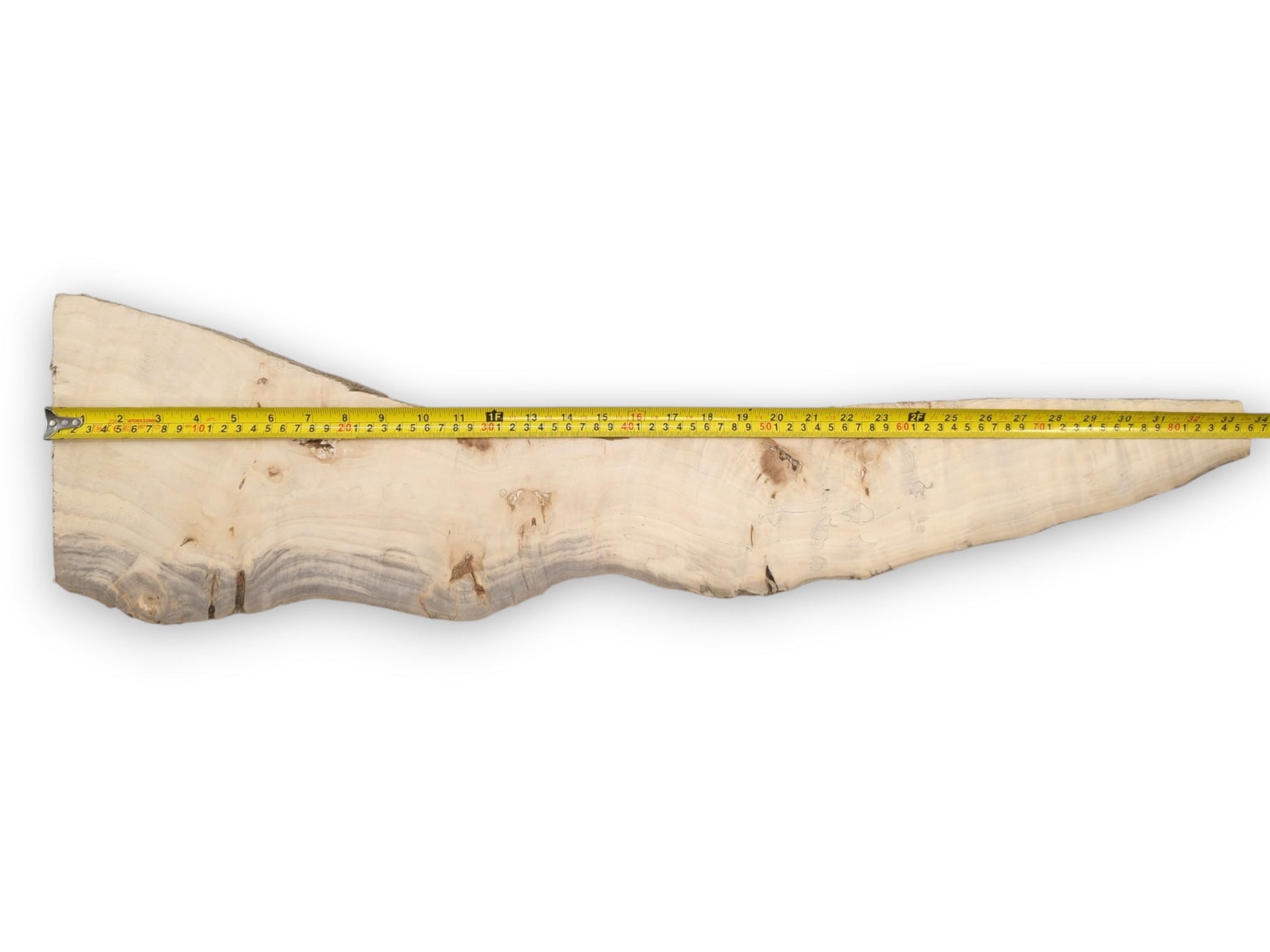 A yellow tape measure spans a long, pale wood plank with a dark, wavy grain.