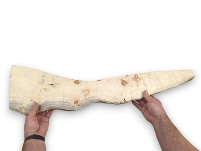 Two hands display a long, pale timber piece that tapers to a slender point.