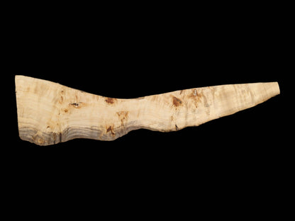 A light-colored timber slab has a dark, flowing stain along its curving live edge.