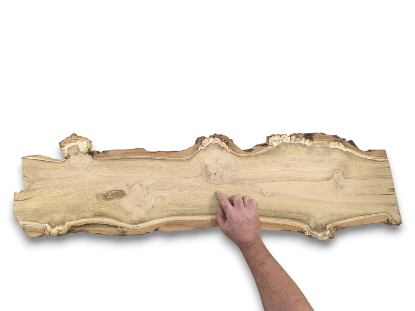 A hand points to the smooth surface of a long, light-colored wood slab with natural bark edges.