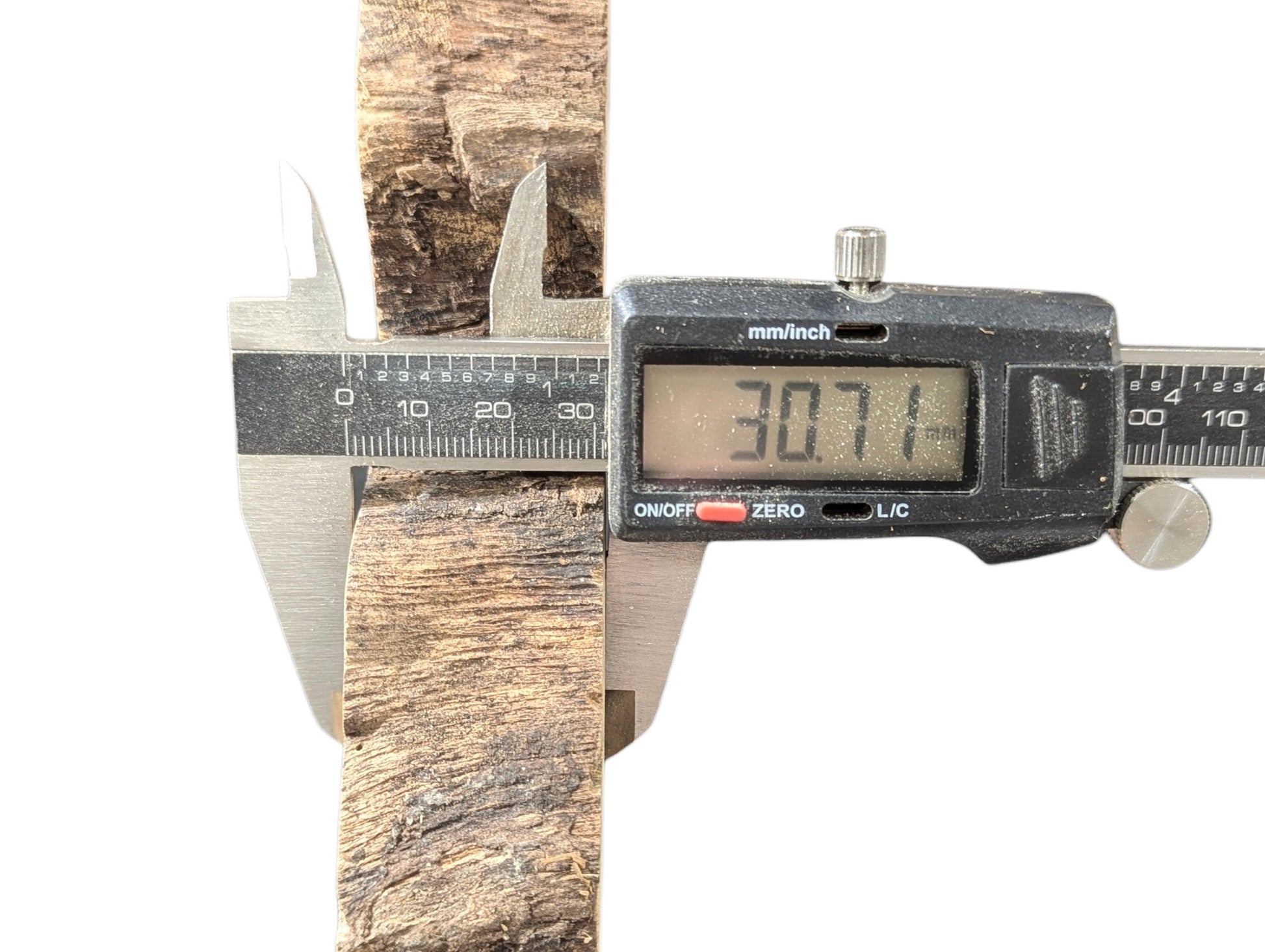 Digital caliper measuring a textured, light brown wood piece, displaying a 30.71mm thickness measurement.