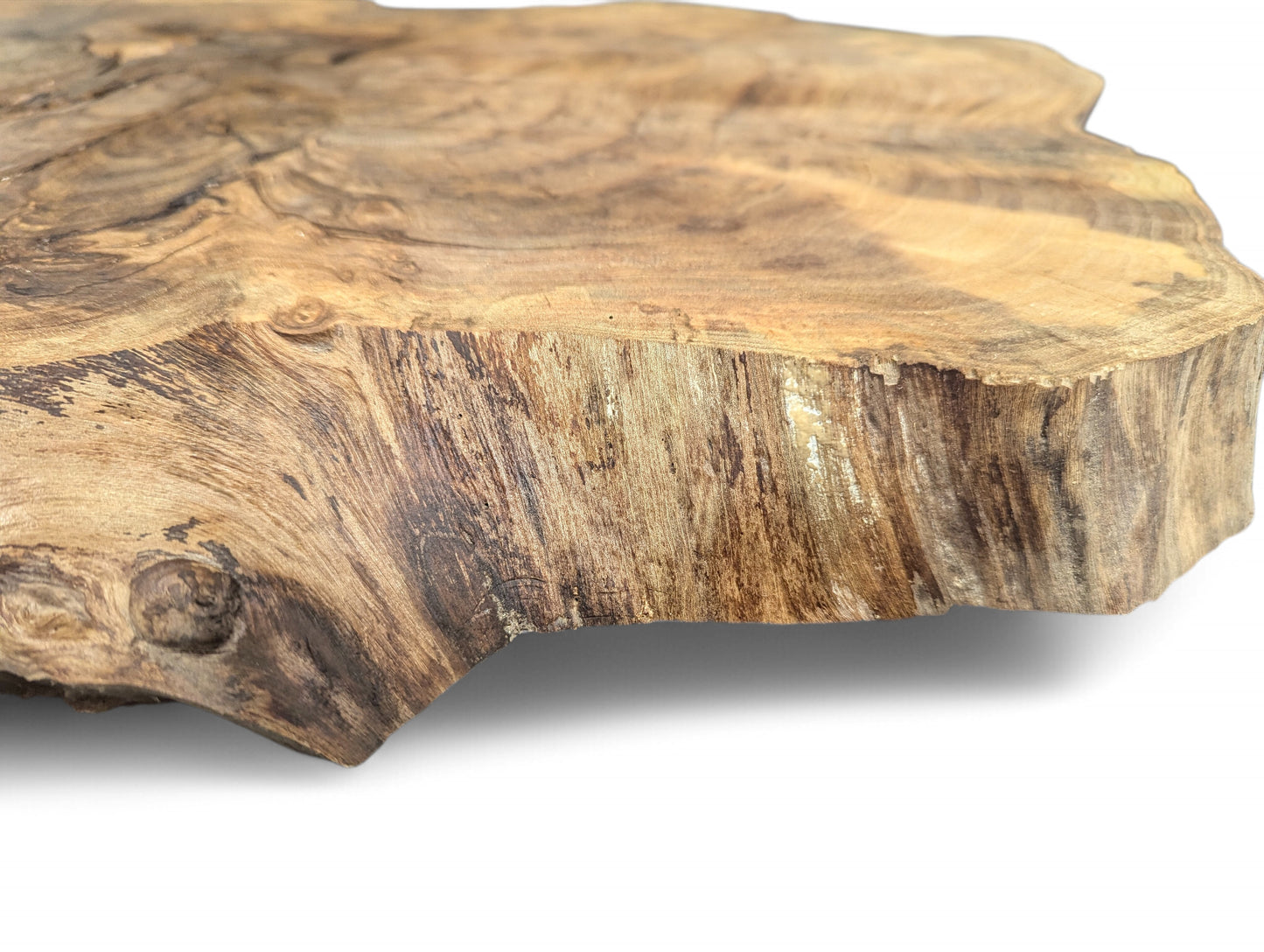 Close-up showing a thick, irregular brown wood slice, its live edge and prominent swirling grain patterns.