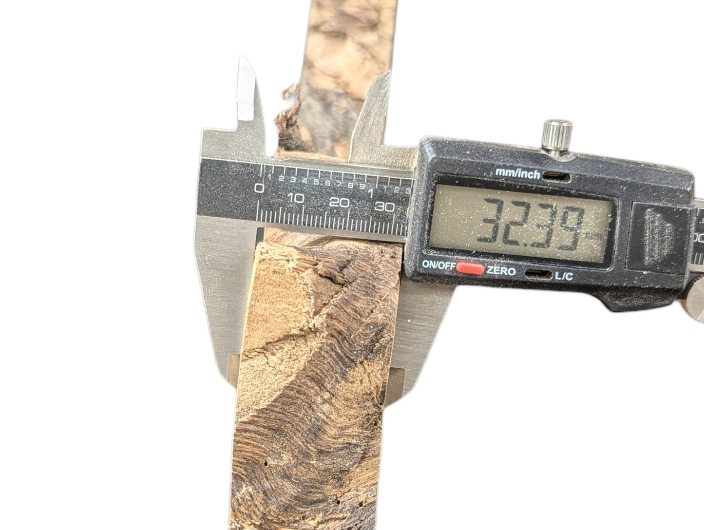 A light brown wood piece with dark swirling grain is measured by digital calipers, reading 32.39 mm.