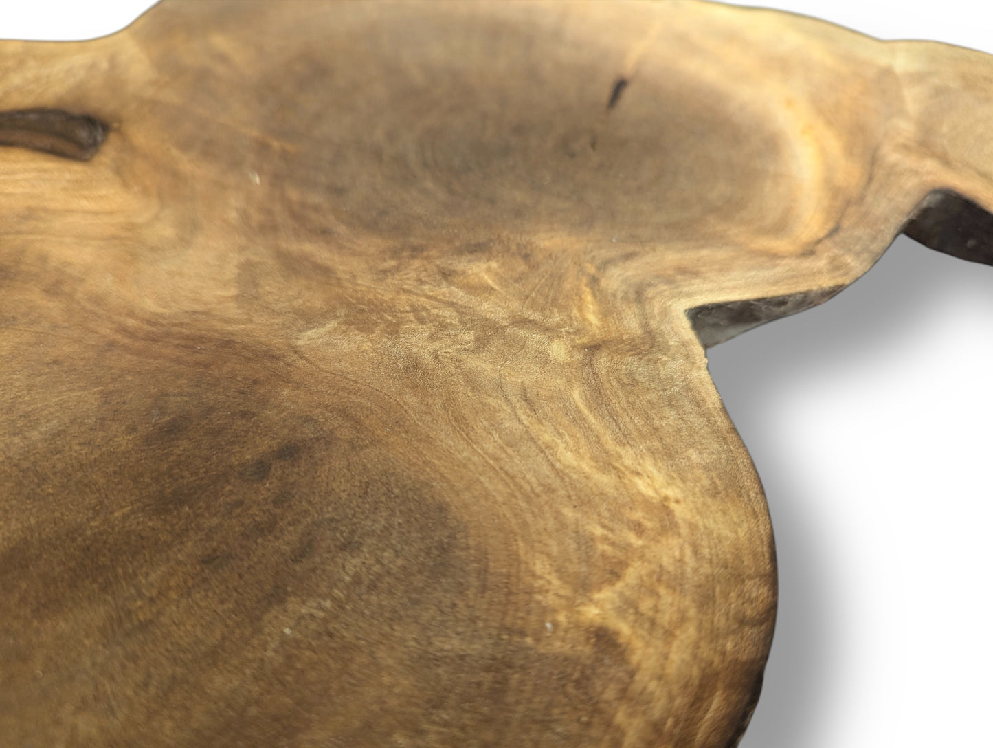 Close-up of an irregular brown wood slice with intricate swirling grain patterns and a visible natural live edge.