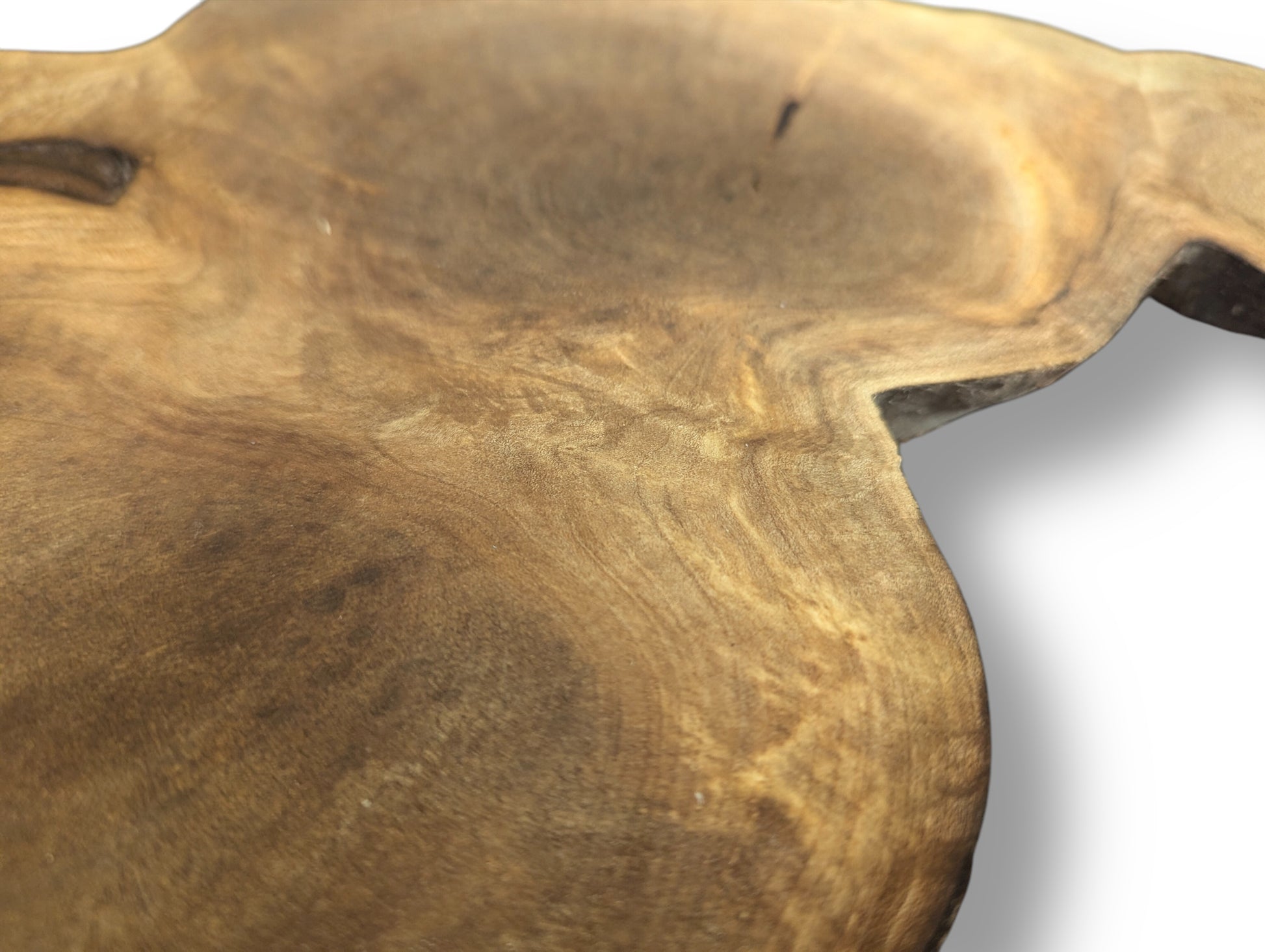 Close-up of an irregular brown wood slice with intricate swirling grain patterns and a visible natural live edge.