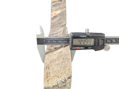 Digital caliper measures the width of a textured, light brown, irregular wood slice, showing 44.99 mm.