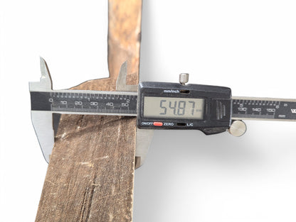 A digital caliper measures the rough, brown side of a wood slice, displaying 54.87mm.