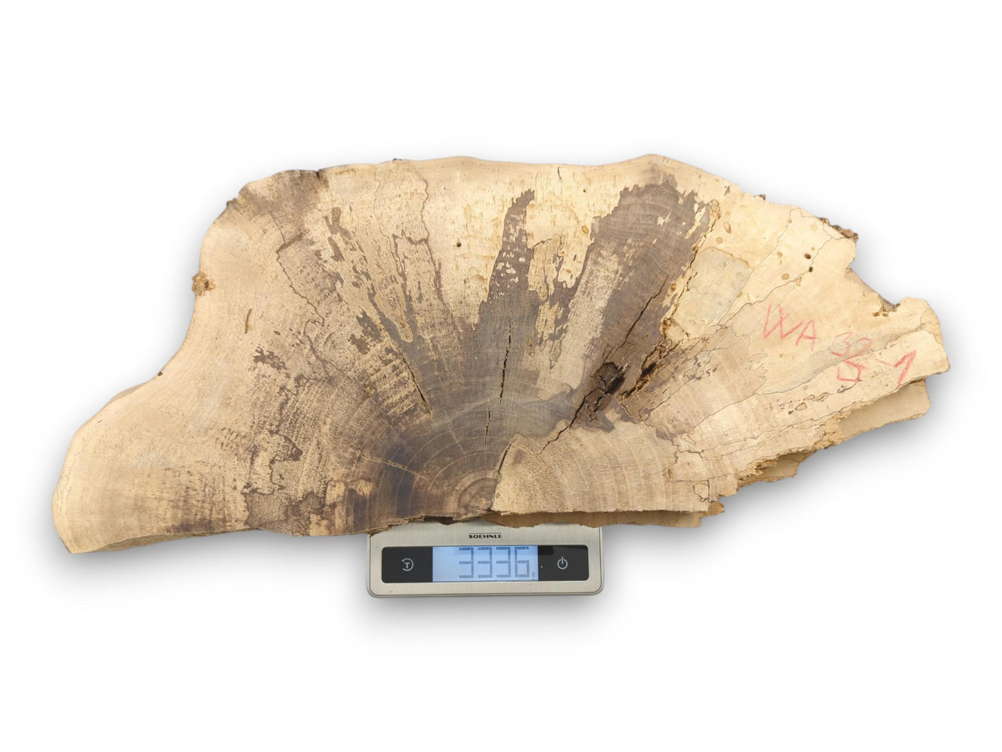 A single walnut slab with a distinct, dark fanned grain pattern rests on a digital scale.