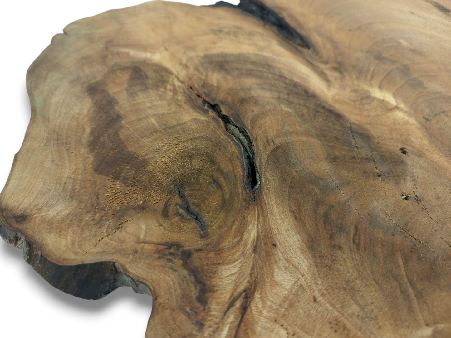 A detailed, angled close-up of a walnut root slab, focusing on its swirling brown grain and dark fissure.