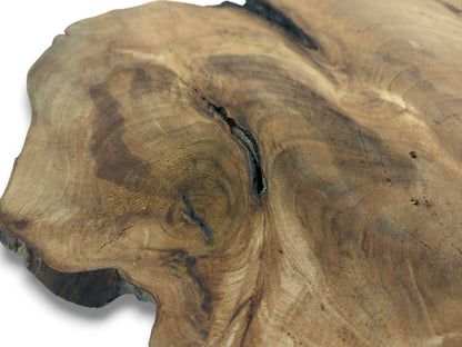 A detailed, angled close-up of a walnut root slab, focusing on its swirling brown grain and dark fissure.