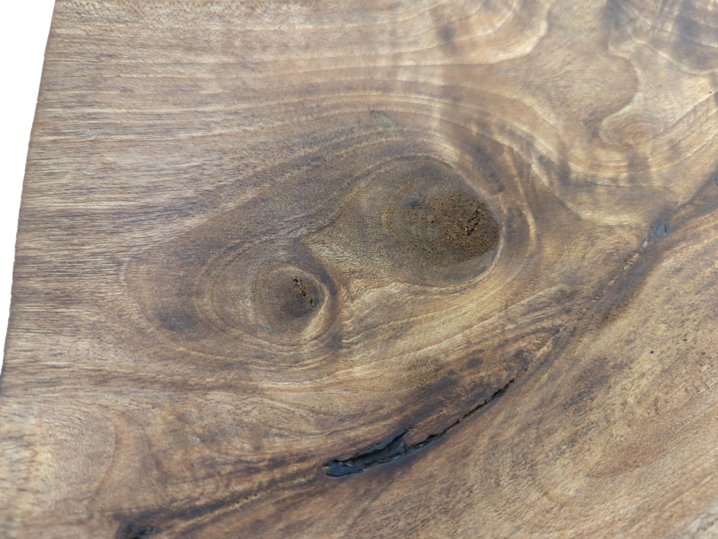 Close-up of a natural walnut wood slice showing swirling grain, knots, and a dark crack.