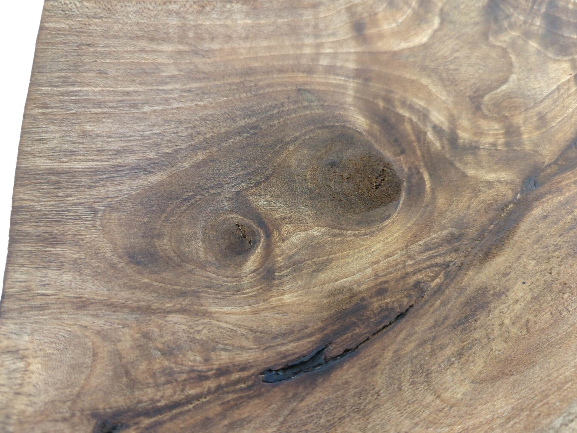 Close-up of a natural walnut wood slice showing swirling grain, knots, and a dark crack.