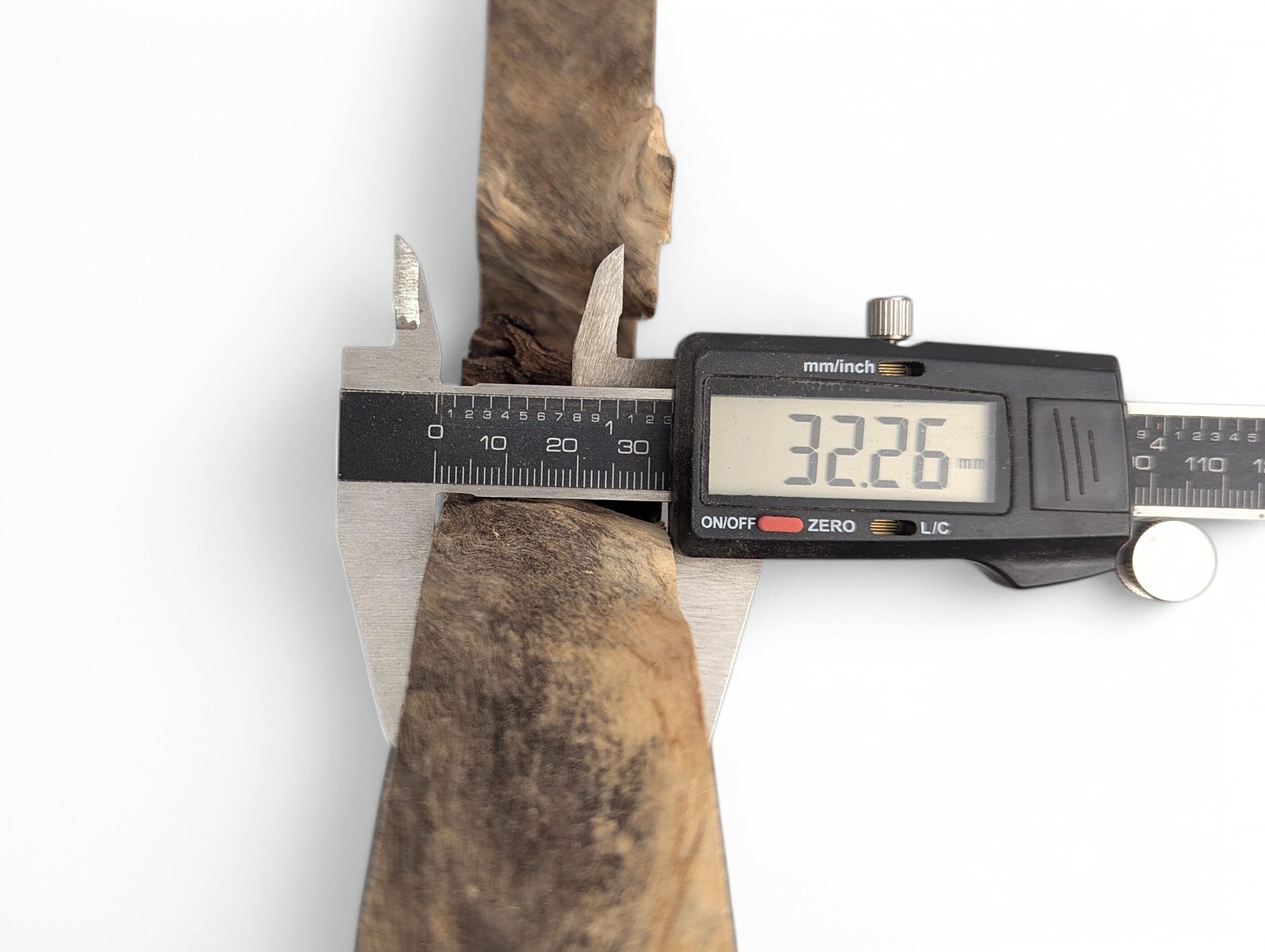 A digital caliper measures an irregular golden-brown live edge wood slice, displaying 32.26 mm thickness.