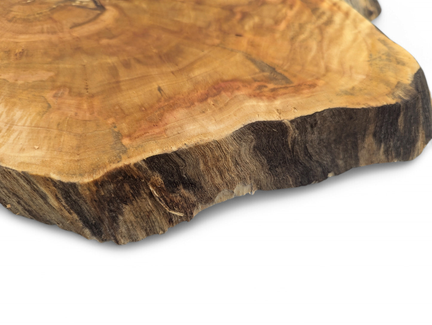 Close-up of an irregular wood slice, golden-brown top with visible growth rings and dark, textured live edge.