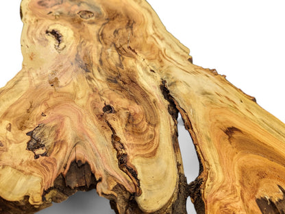 Irregular live edge wood slice with golden-brown colors, prominent swirling grain, and a deep natural fissure.