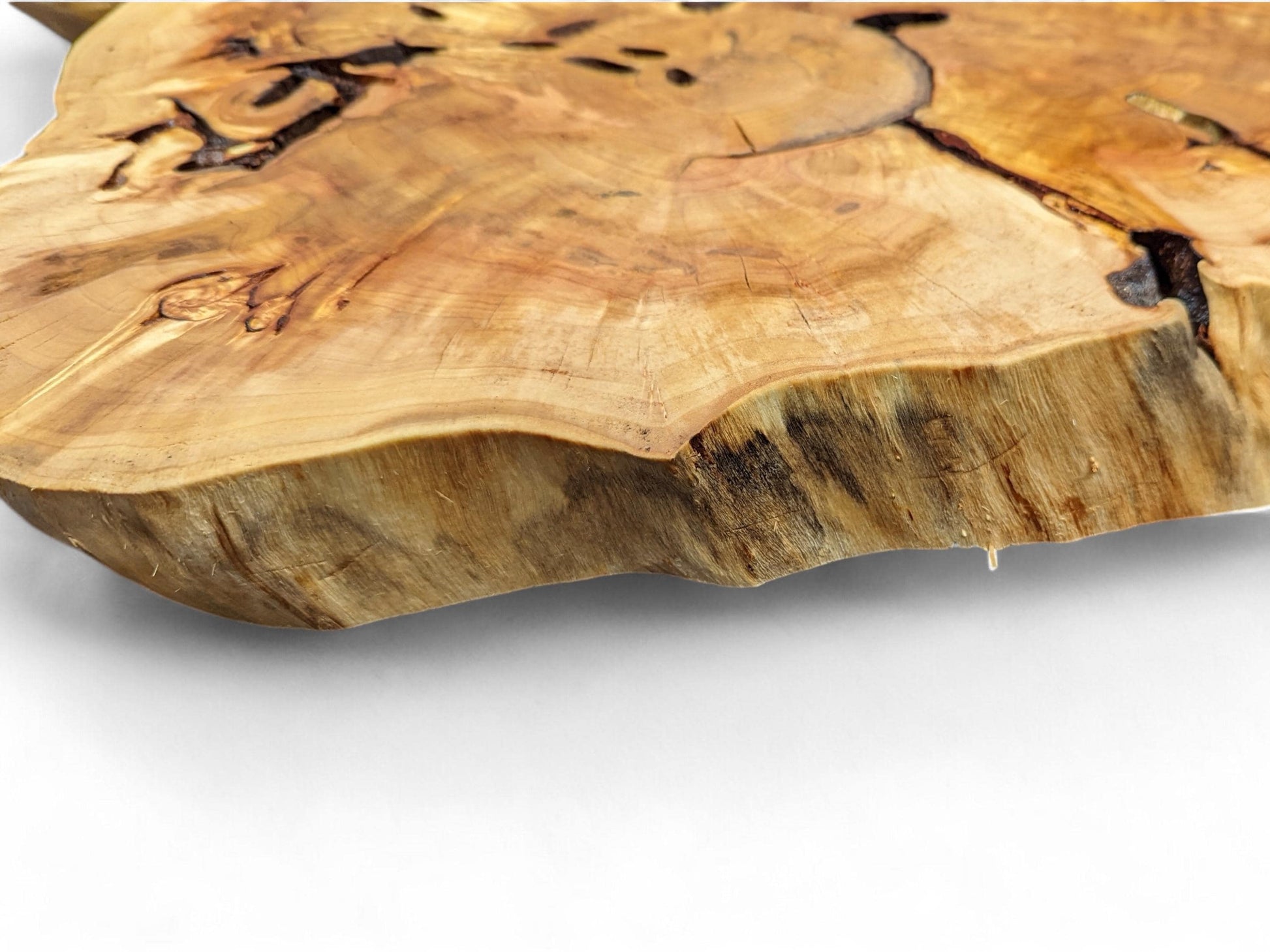 Thick, golden-brown wood slice showing natural grain patterns, dark inclusions, and a textured live edge.