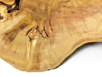 Irregularly shaped, light brown wood slab with prominent grain rings, natural knots, and a dark live edge.