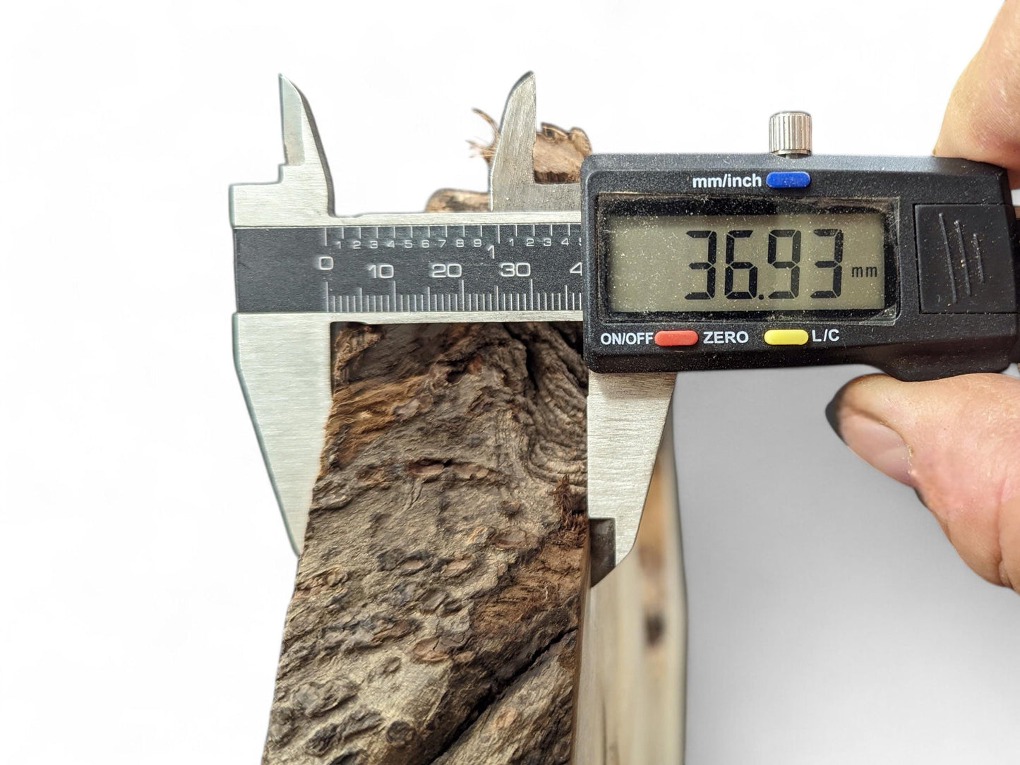 A digital caliper measures a dark, textured live edge wood piece, displaying 36.93 mm on its screen.