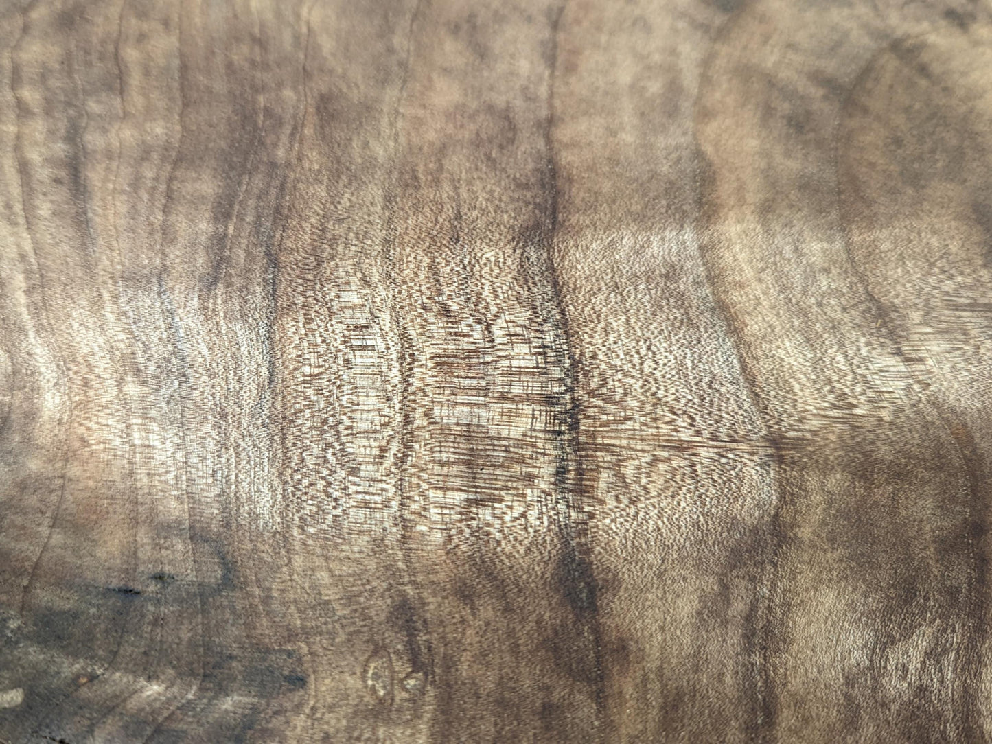 Walnut wood surface featuring prominent, swirling light and dark brown grain patterns and a visible fine texture.