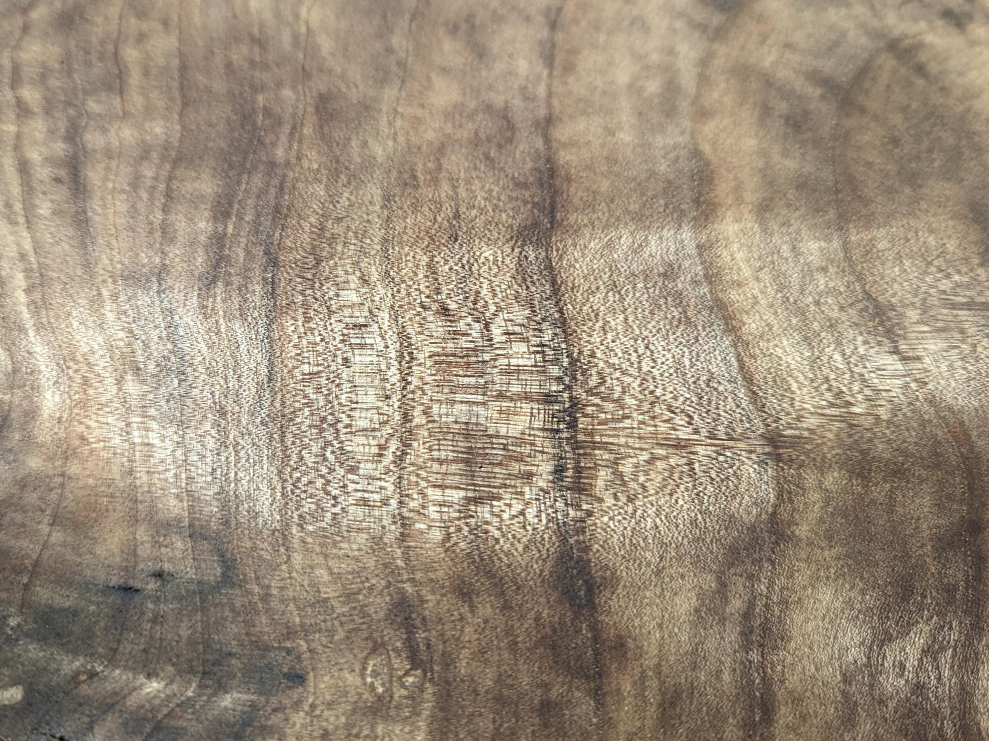 Walnut wood surface featuring prominent, swirling light and dark brown grain patterns and a visible fine texture.