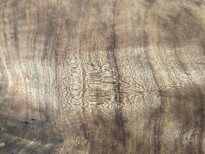 Walnut wood surface featuring prominent, swirling light and dark brown grain patterns and a visible fine texture.