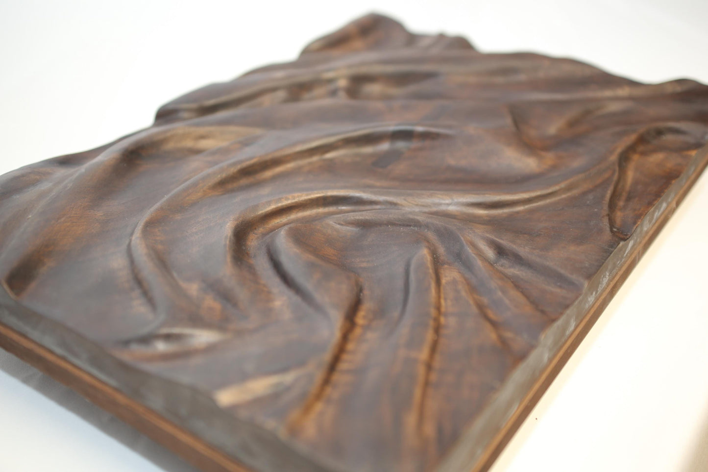 Deeply carved dark brown solid walnut wall art, displaying fabric-like folds with natural oil finish.