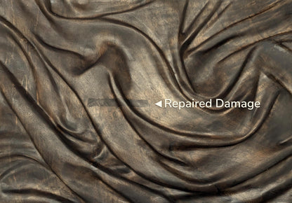 A close-up of dark, carved wood with a text overlay indicating a repaired area.