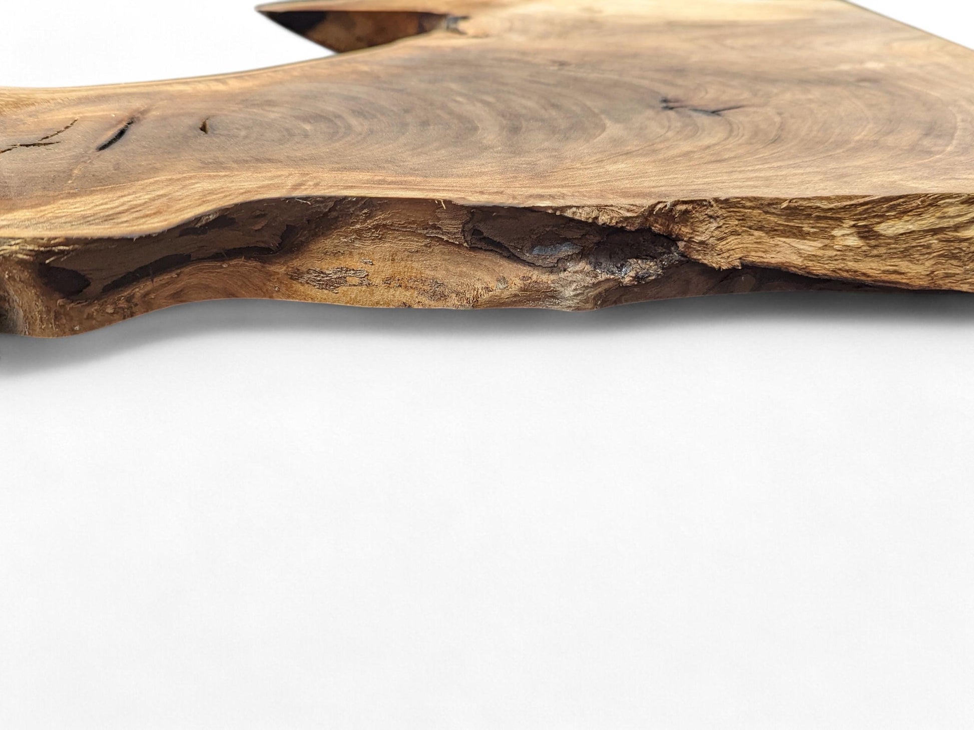 Light brown live edge walnut wood slice displaying natural grain, knots, and a textured, irregular side.