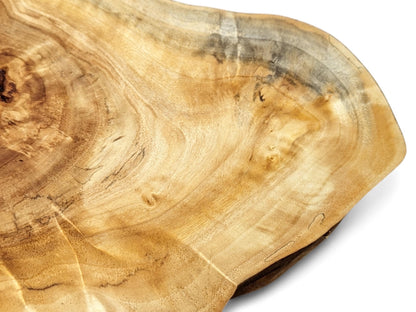 An irregular wood slice shows light brown color, prominent wavy grain, and darker streaks.