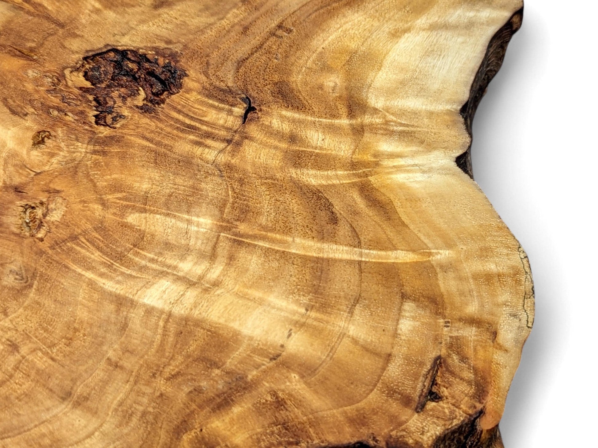 Close-up of a light brown, irregularly shaped wood slice with distinct wavy grain and a dark natural void.