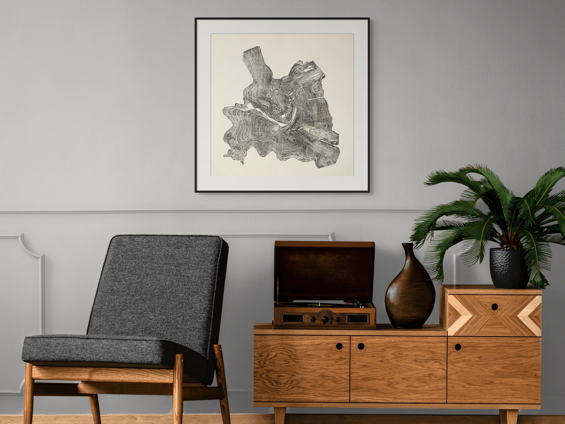 Black and white framed tree root monoprint centered on a gray wall above a wooden console cabinet.