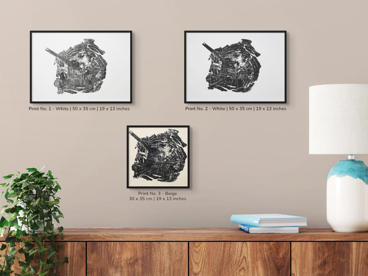 Image features three framed black woodcut tree root prints with text, a plant, lamp, and books.